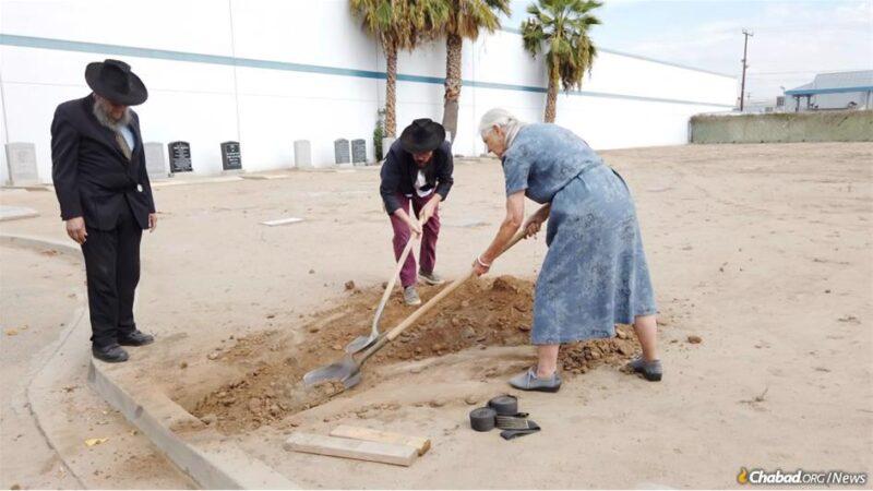 Baruch Bloom, left, Rabbi Yonasan Abrams and Penelope Frey gently shovel some dirt over the fresh grave