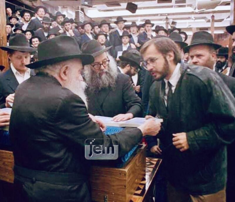 Nochum Litkowski receiving a kuntres from the Rebbe * Photo: JEM