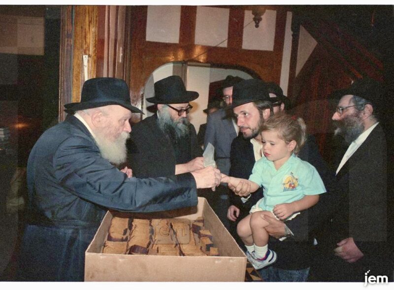 Nochum Litkowski and his child receive lekach from the Rebbe on 9 Tishrei 5749 * Photo: JEM