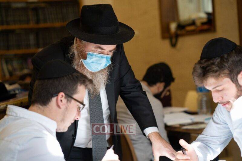 A masked Rabbi Kasriel Shemtov talks with a student at the Mayanot Men_s Program