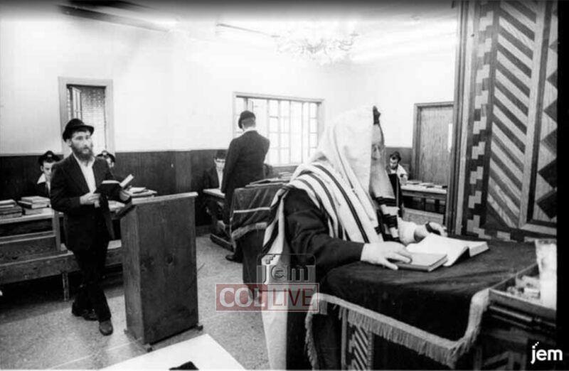 R' Mendel Okunov (left) in the small zal of 770 as Rosh Yeshiva Rabbi Mordechai Mentlick stands chazzan